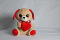 Peluche de perrito con corazon en la mano